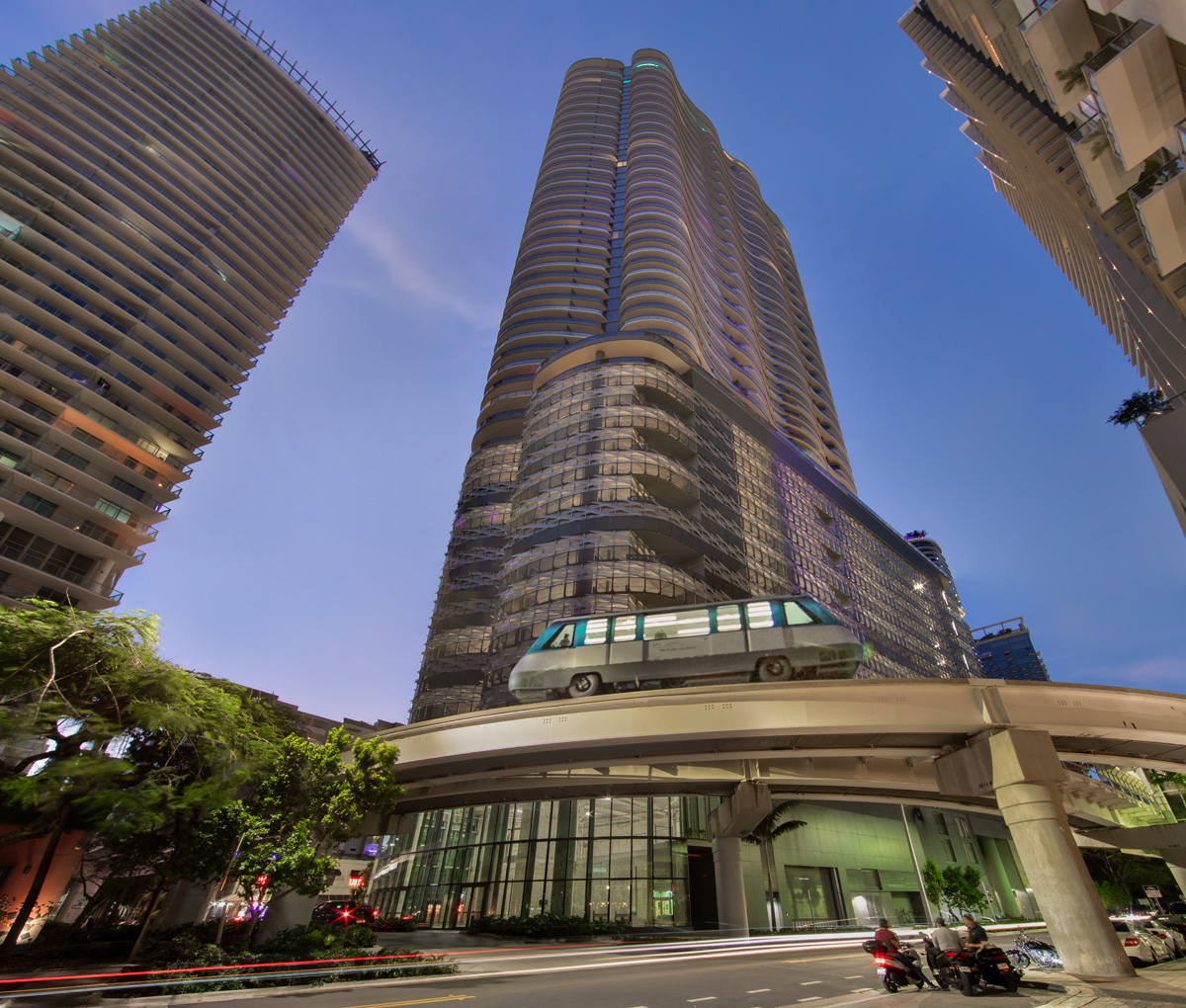 Architectural dusk view of Brickell Flatiron tower and metro mover in downtown Miami