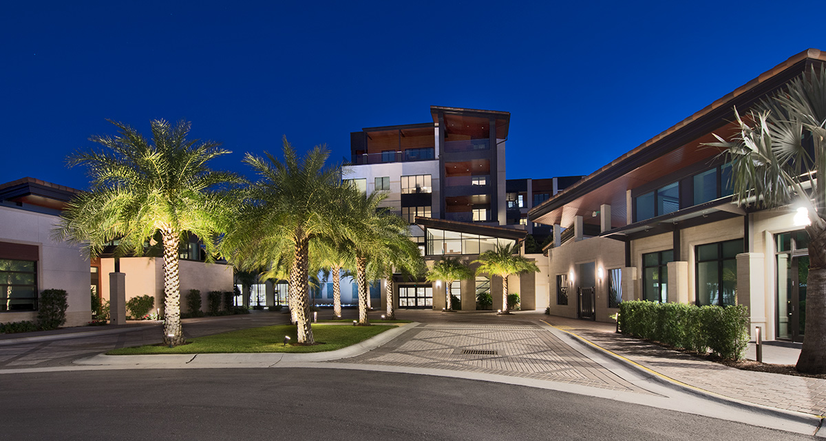 Architectural dusk view of Moorings Park at Grey Oaks senior living in Naples, FL.